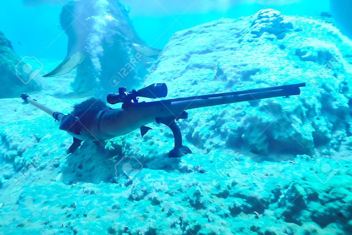 underwater hunter lies at the bottom of the sea with a crossbow in anticipation of a shot at the fish