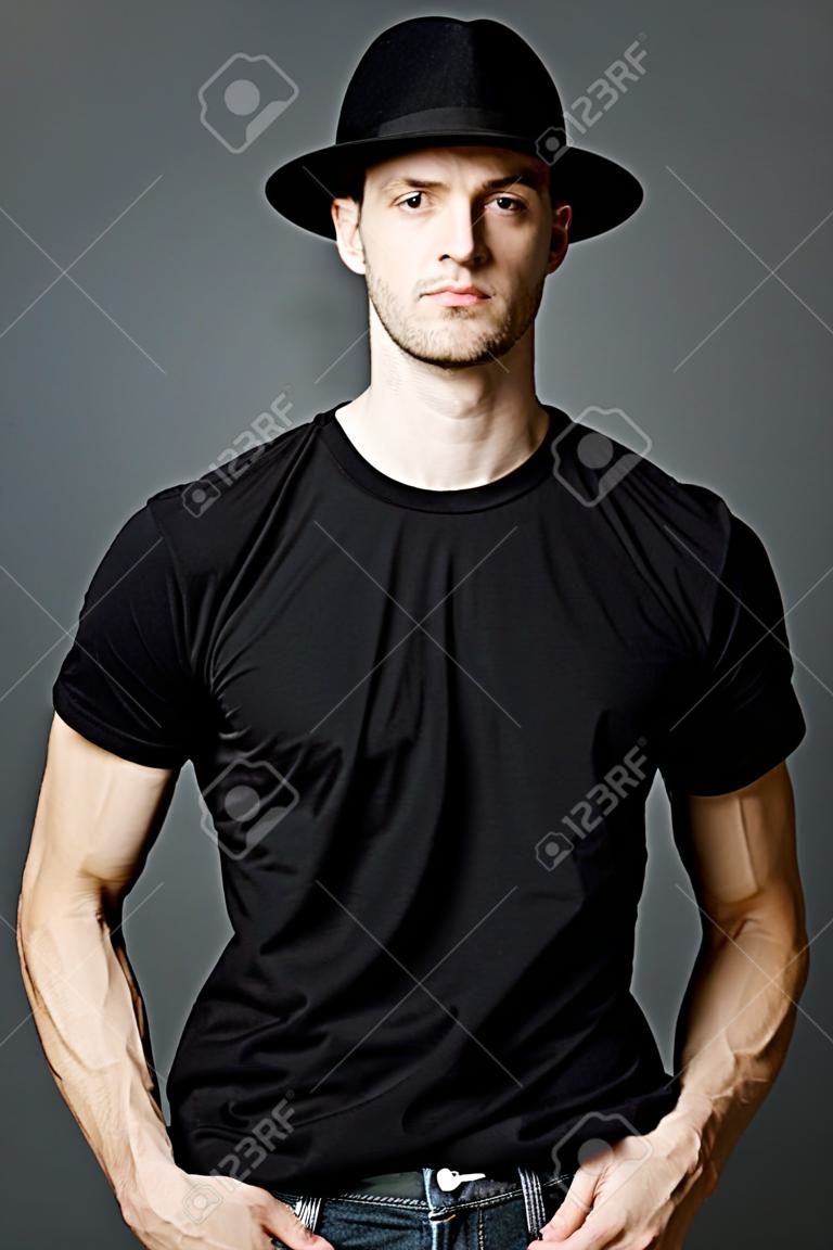 Young handsome man posing in black t-shirt and black hat.