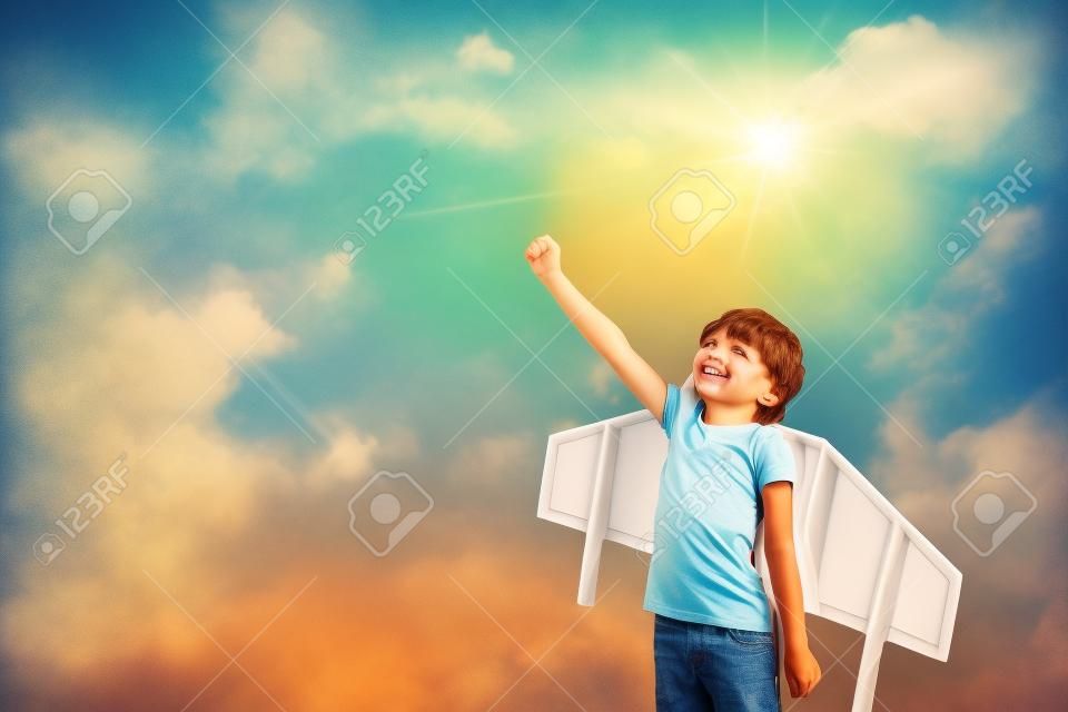 Boldog gyermek játszik a játék szárnya elleni nyári égbolt háttere. Retro tónusú
