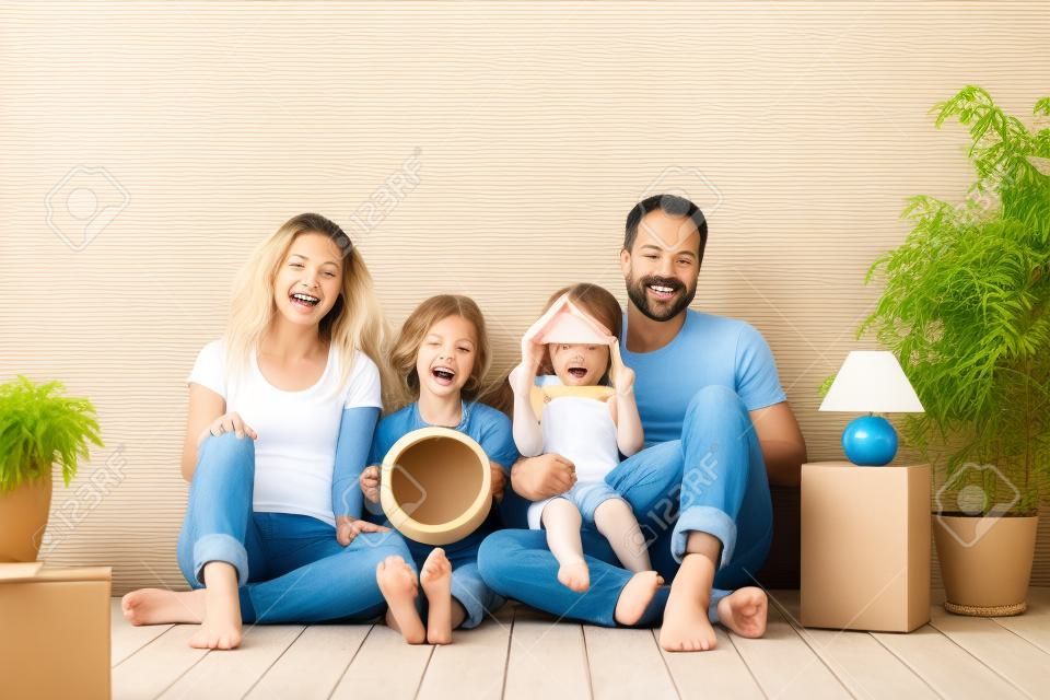 Famiglia felice con due bambini che giocano nella nuova casa. Padre, madre e figli si divertono insieme. Giorno del trasloco e concetto di bene immobile