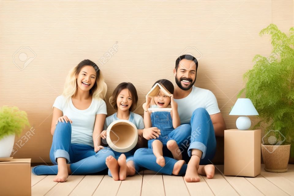 Gelukkige familie met twee kinderen spelen in een nieuw huis. Vader, moeder en kinderen hebben plezier samen.