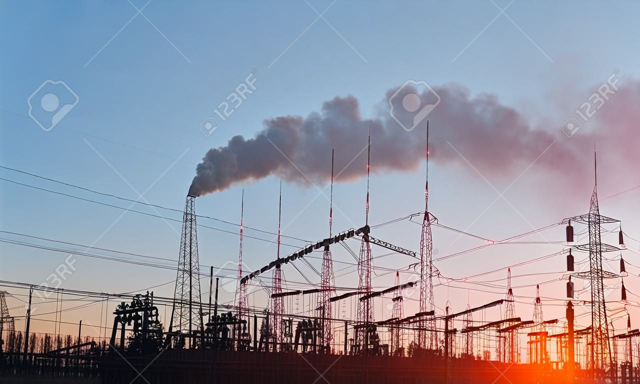 Umspannwerk mit Stromleitungen und Transformatoren bei Sonnenuntergang