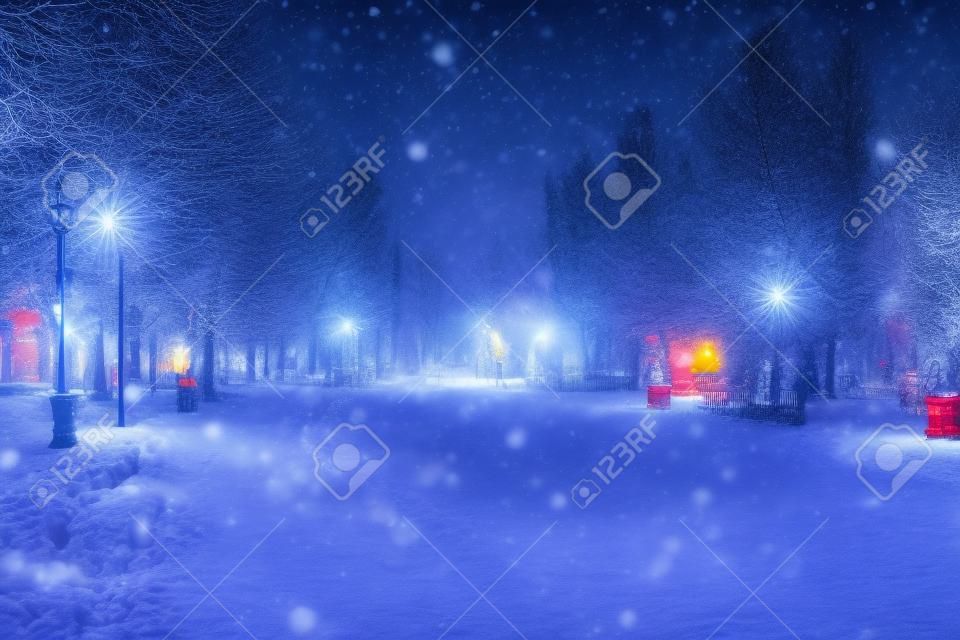 Blured photo of a winter night park with lanterns and Christmas decorations in heavy snowfall.