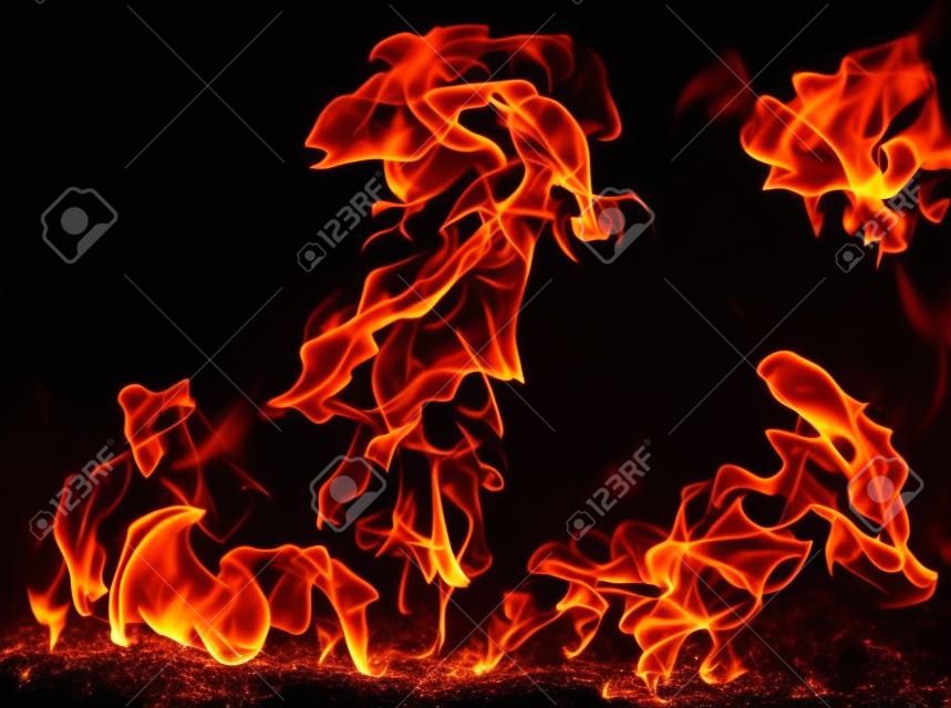 Płomienie ognia na czarnym tle izolowany płonący gaz lub benzyna pali się ogniem i płomieniami płonące płonące iskry z bliska wzory ognia piekielny blask ognia w ciemności z przestrzenią do kopiowania