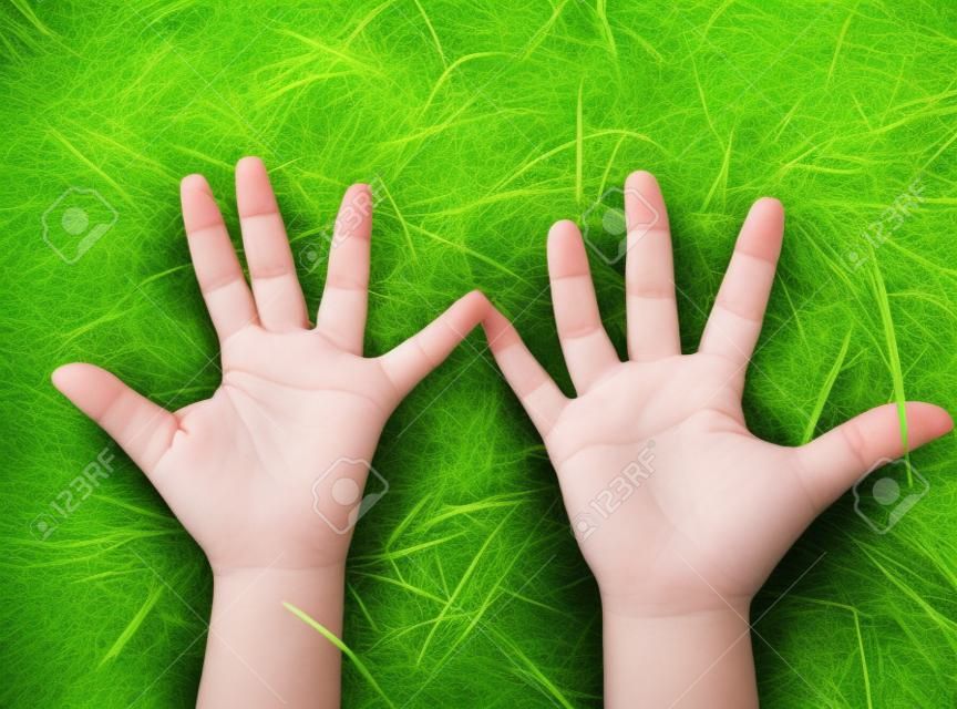 Sosteniendo la parte del cuerpo de la mano de los niños con fondo de hierba verde