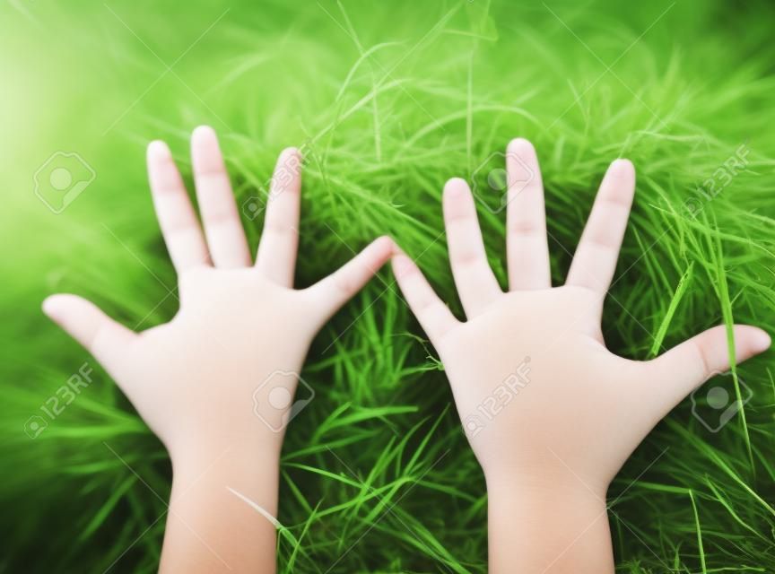 Sosteniendo la parte del cuerpo de la mano de los niños con fondo de hierba verde