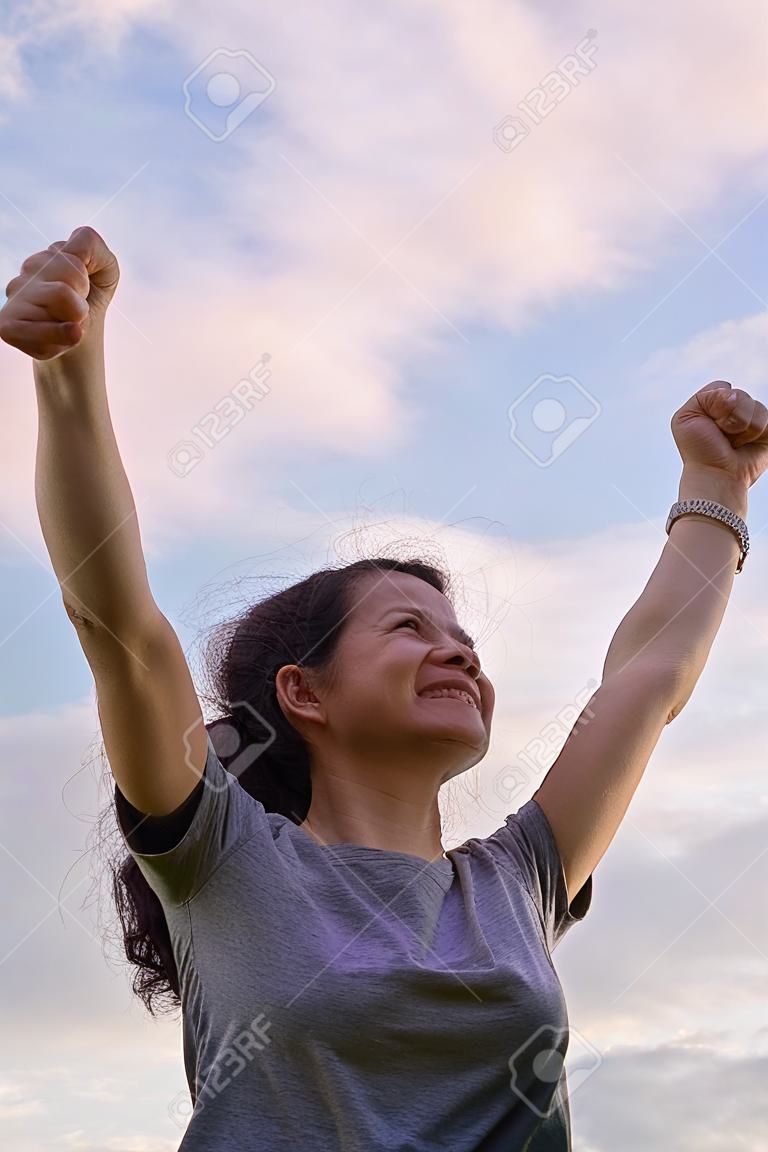Une seule figure féminine avec un geste de félicitation pour le succès avec un ciel lumineux en arrière-plan