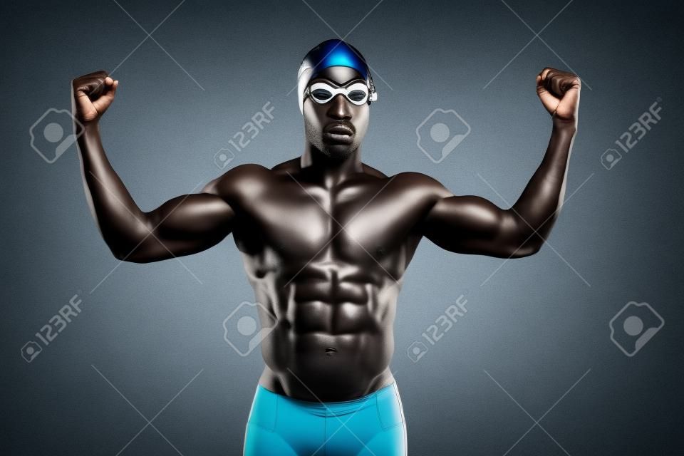 Athletisch muskulös schwarze afrikanische Schwimmer Tragen einer Schutzbrille und Schutzkappe. Studioaufnahme vor grau.