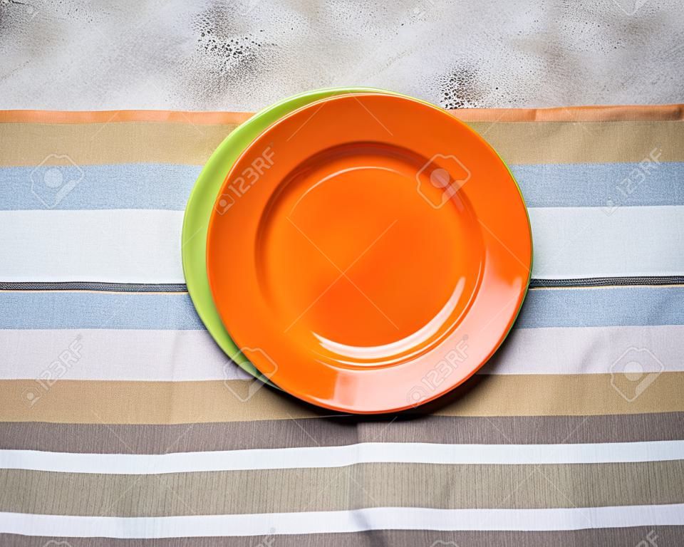 Empty orange and green plates on concrete table
