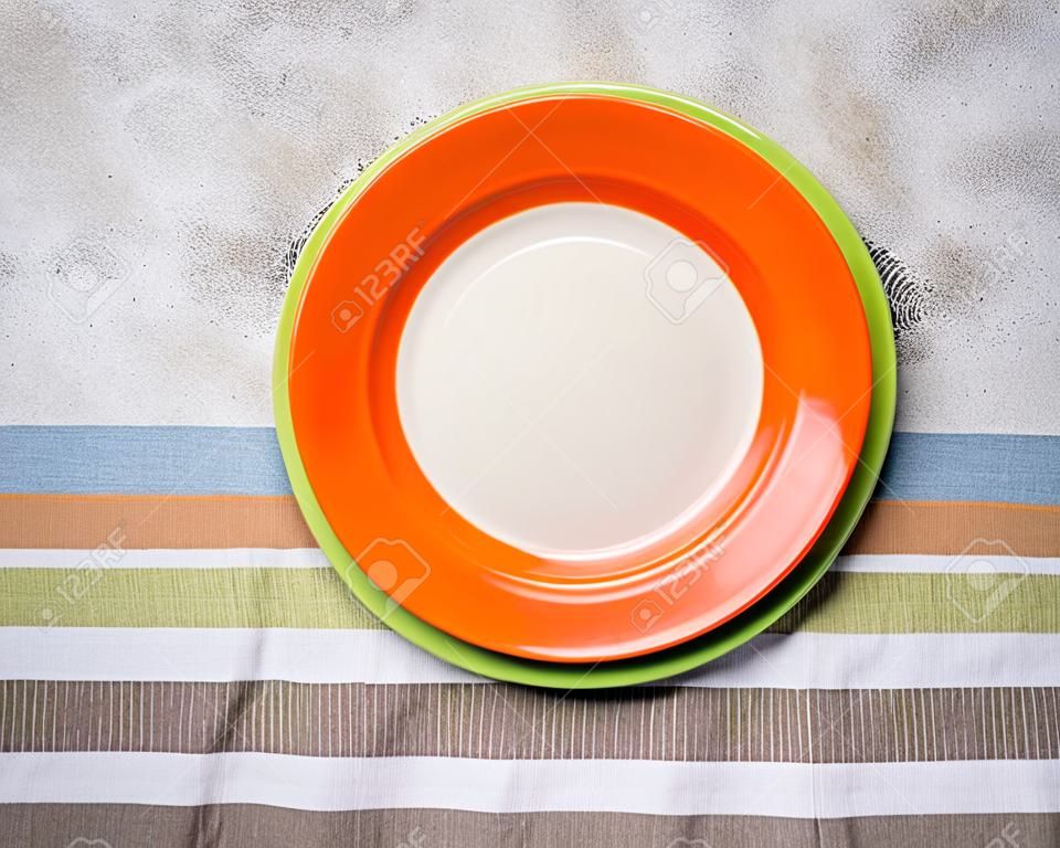 Empty orange and green plates on concrete table