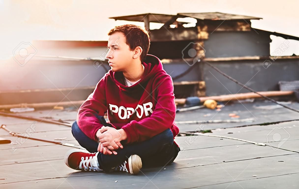 Frasobliwy nastolatka siedzi na dachu domu