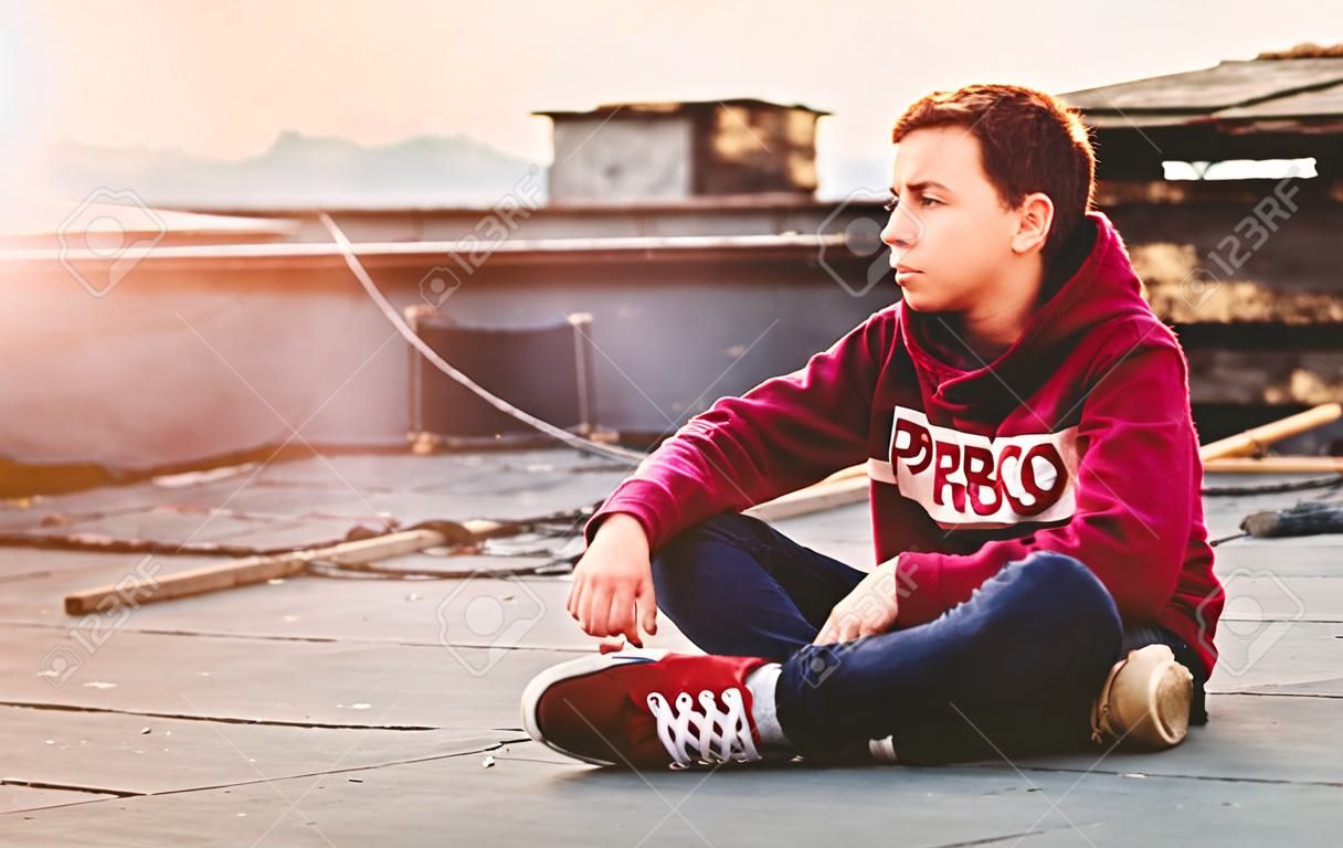 adolescent pensif assis sur le toit de la maison