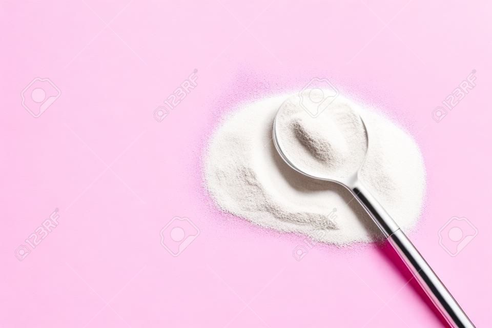 Collagen powder on pink background. Extra protein intake. Natural beauty and health supplement for skin, bones, joints and gut. Plant or fish based. Flatlay, top view. Copy space for your text.