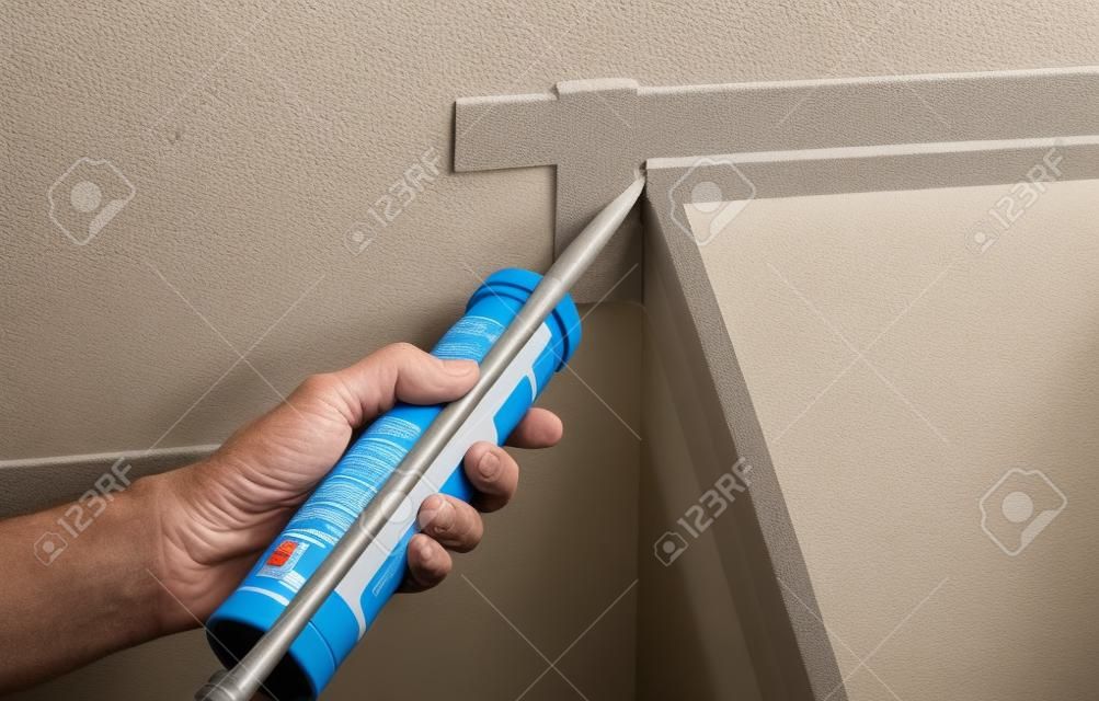 El trabajador pone sellador de silicona para sellar la junta entre la bañera  y la pared.