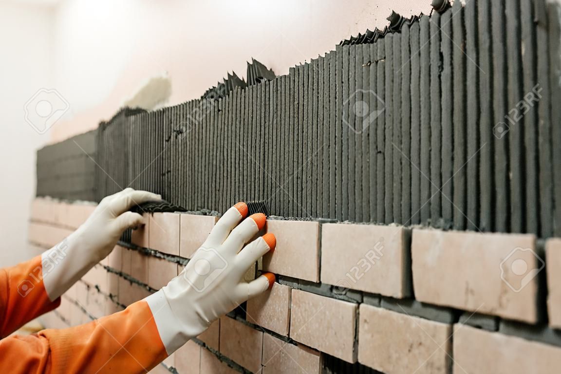Instalación de los azulejos de la pared. Un trabajador puesta azulejos en forma de ladrillo.