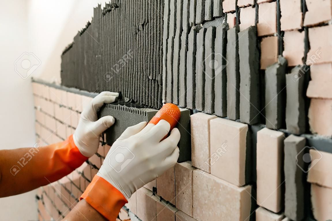 Instalación de los azulejos de la pared. Un trabajador puesta azulejos en forma de ladrillo.