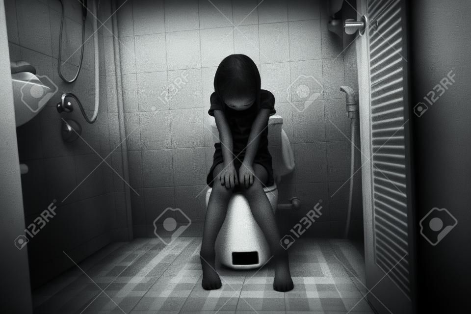 peur et déprimer la jeune fille assise dans les toilettes, ton blanc, concept d'abus d'enfant