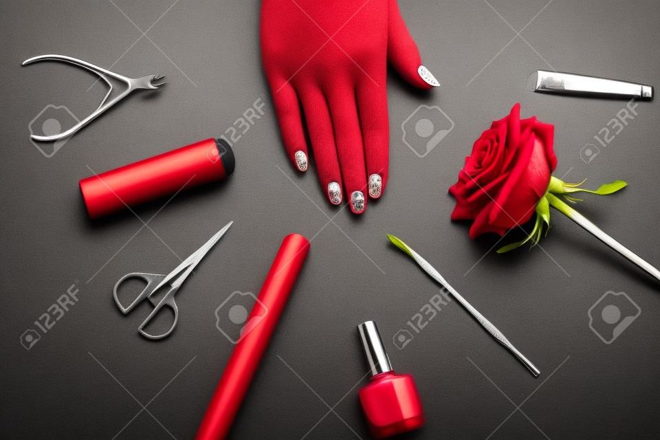 La mano della donna con le unghie finite. Set manicure di strumenti e rosa rossa. Consigli per unghie sane e ben curate.