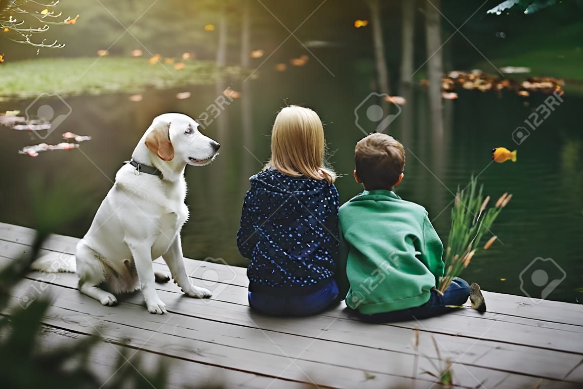 dziewczynka, chłopiec i pies bawi się na dworze - imitują połów na jeziorze