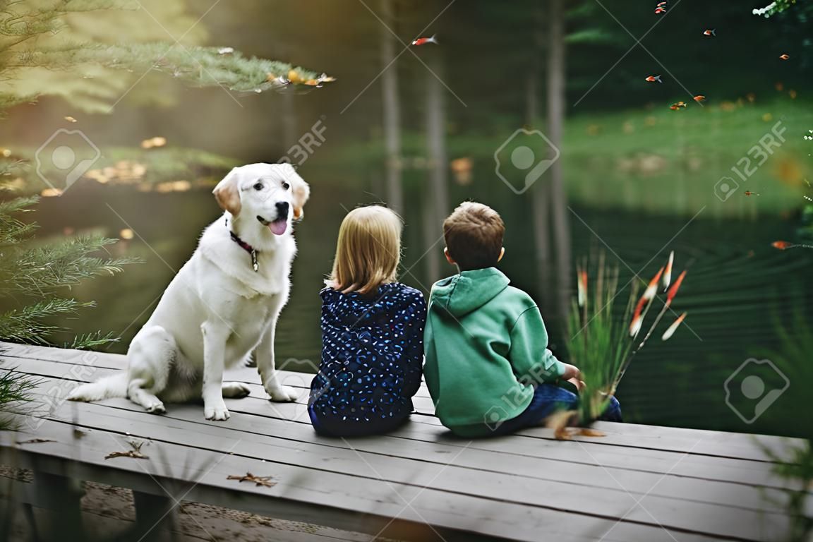 dziewczynka, chłopiec i pies bawi się na dworze - imitują połów na jeziorze