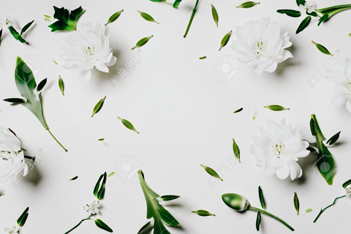 Beautiful floral pattern made of white floral, green leaves, branches on white background with a drawn frame. Flat lay, top view. Spring background.
