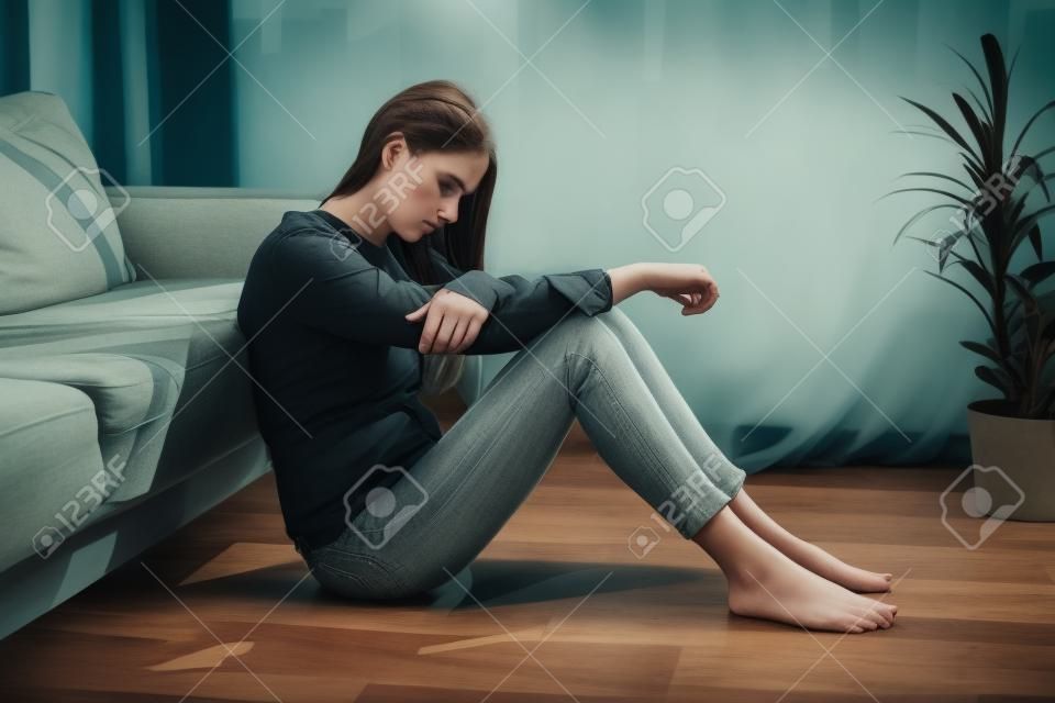Déprimée triste inquiète jeune femme brune assise sur le sol seule troublée par la solitude, contrariée par le problème mental de la solitude, pense à l'avortement regrette la mauvaise erreur, la rupture ou le concept de divorce