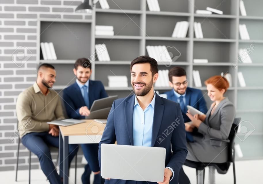 employee of the company with laptop on the background of business team