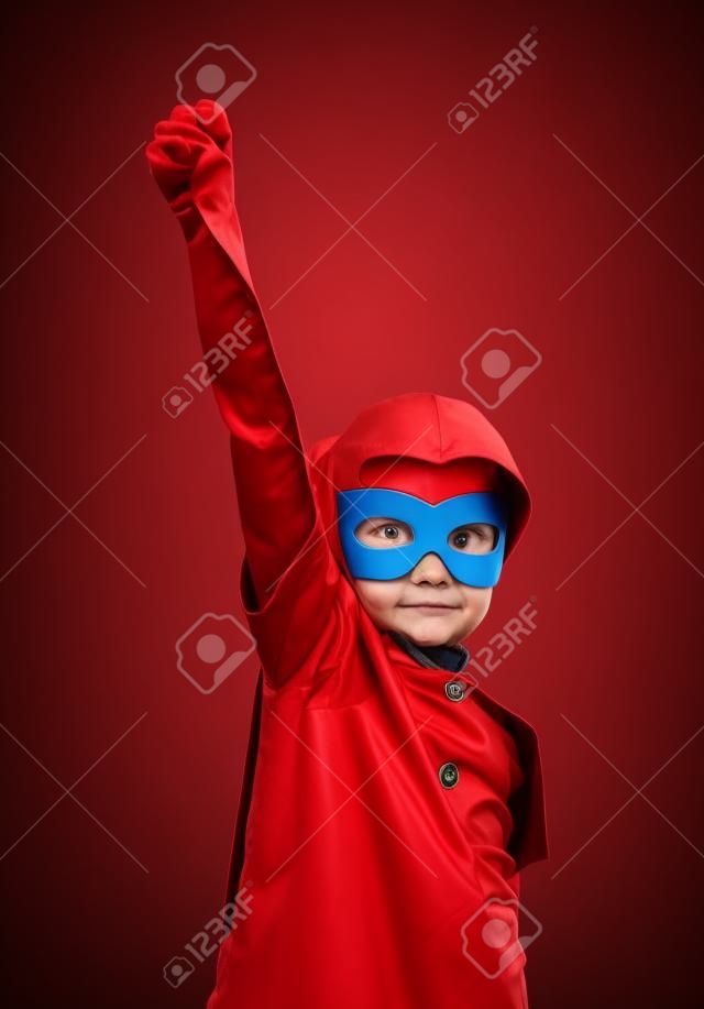 Lustige kleine Macht Superheld Kind (Mädchen) in einem roten Regenmantel. Superhero Konzept. Instagram Farben Muskelaufbau