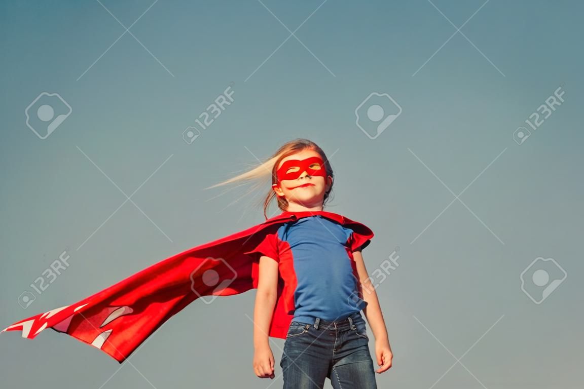 Funny little power super hero child (girl) in a red raincoat. Superhero concept.
