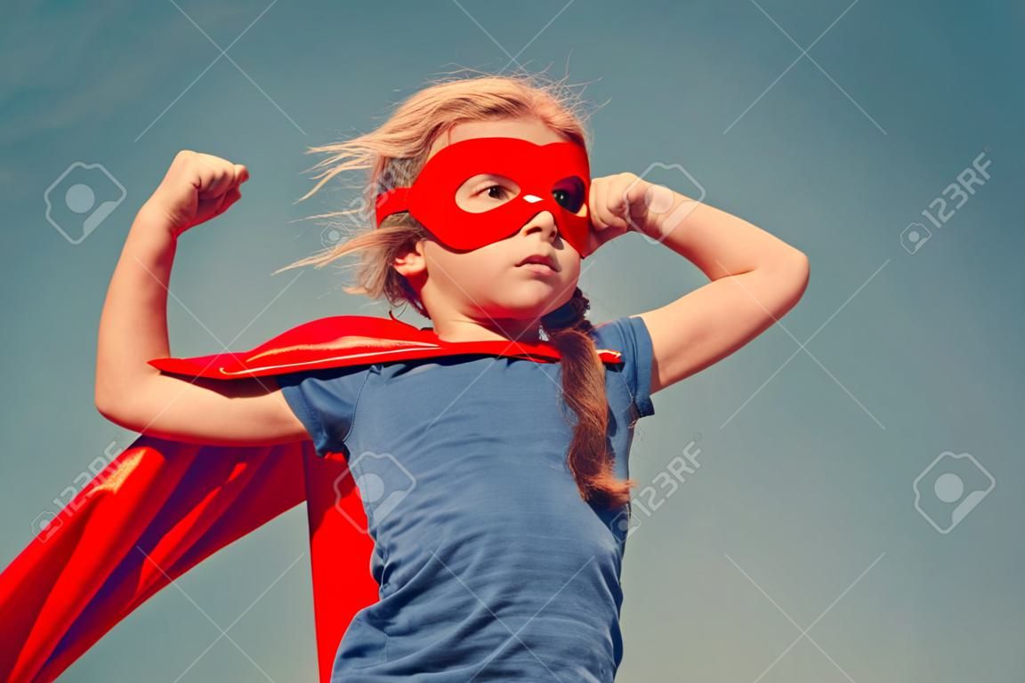 Funny little power super hero child (girl) in a red raincoat. Superhero concept.