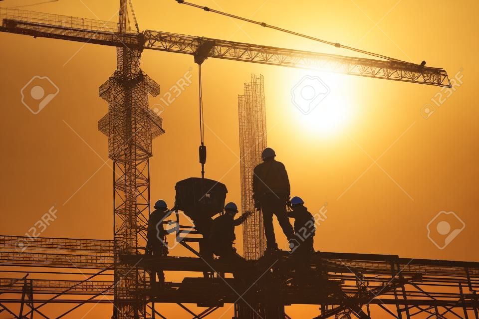 Trabajadores de la construcción e ingenieros que trabajan en alta seguridad cerca de la grúa torre. Industria pesada y concepto de seguridad en el trabajo.