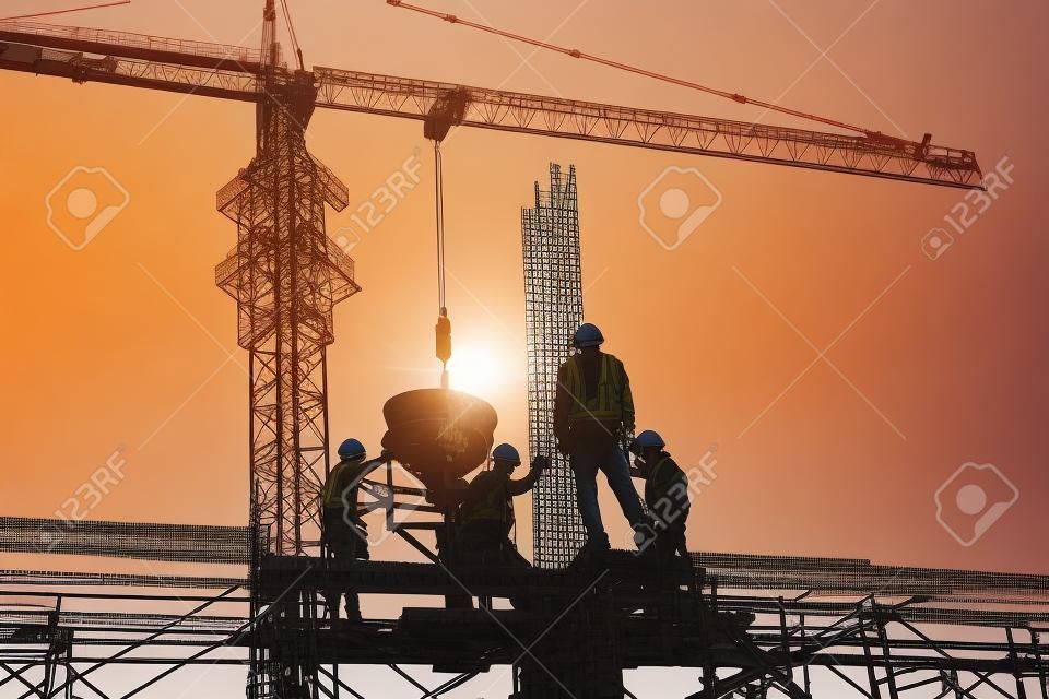 Trabajadores de la construcción e ingenieros que trabajan en alta seguridad cerca de la grúa torre. Industria pesada y concepto de seguridad en el trabajo.