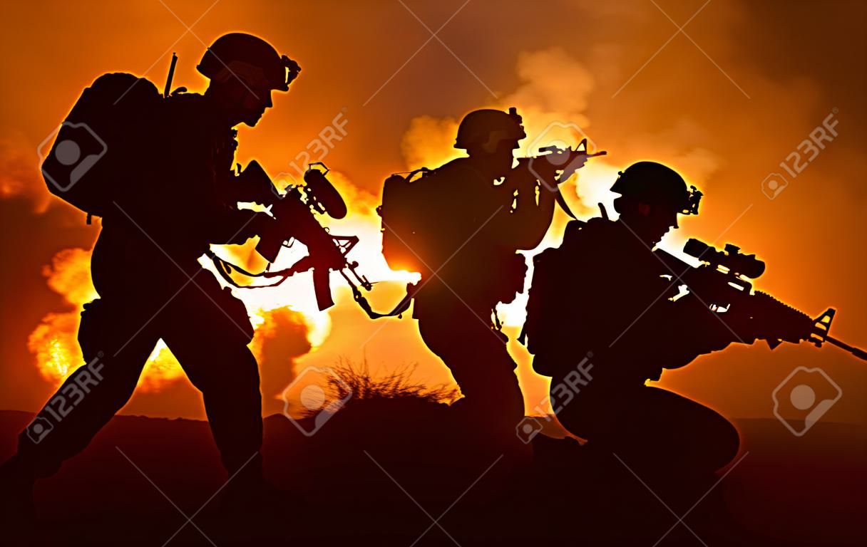Silhouettes van twee legersoldaten, Amerikaanse mariniers team in actie, omsingeld vuur en rook, schieten met aanvalsgeweer en machinegeweer, aanval vijand met onderdrukkende geweerschoten tijdens offensieve missie