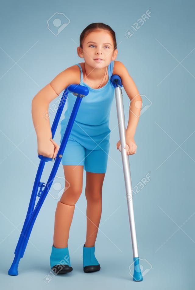 Uma jovem luta para andar com muletas após lesões no braço e na perna.