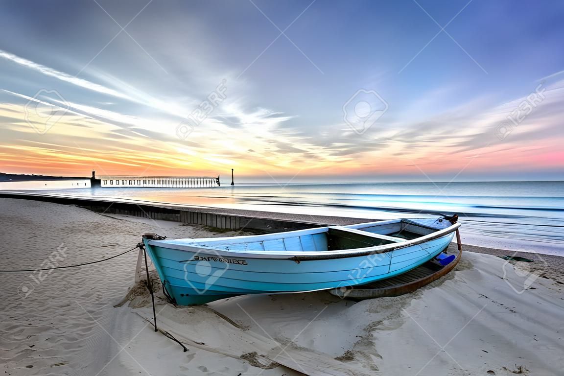 碧藍的漁船在日出伯恩茅斯沙灘碼頭遠的距離