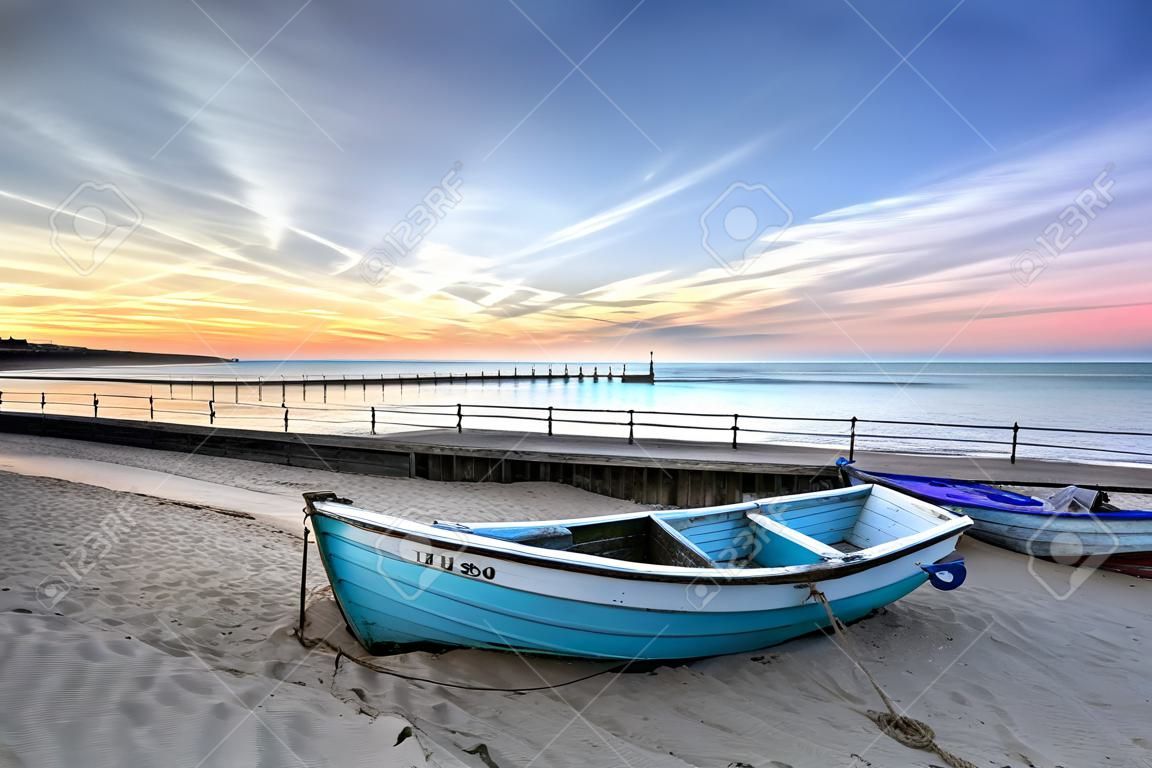 碧藍的漁船在日出伯恩茅斯沙灘碼頭遠的距離