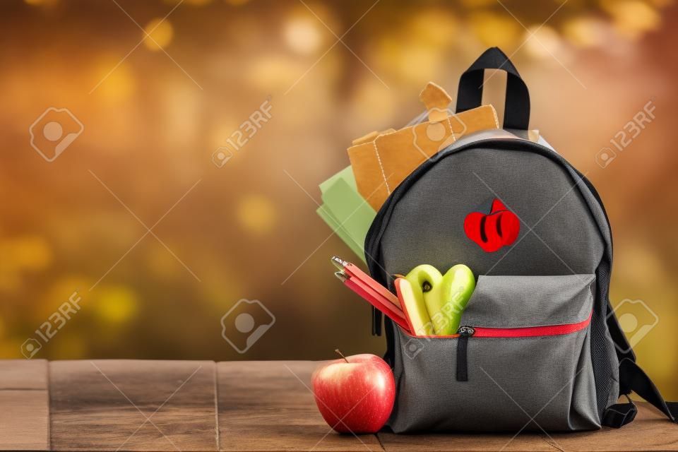 Full School backpack with apple on wooden and nature background