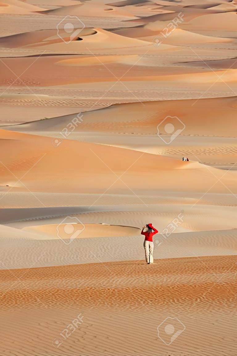 A woman photographing sand dunes in the Rub al Khali or Empty Quarter. Straddling Oman, Saudi Arabia, the UAE and Yemen, this is the largest sand desert in the world.