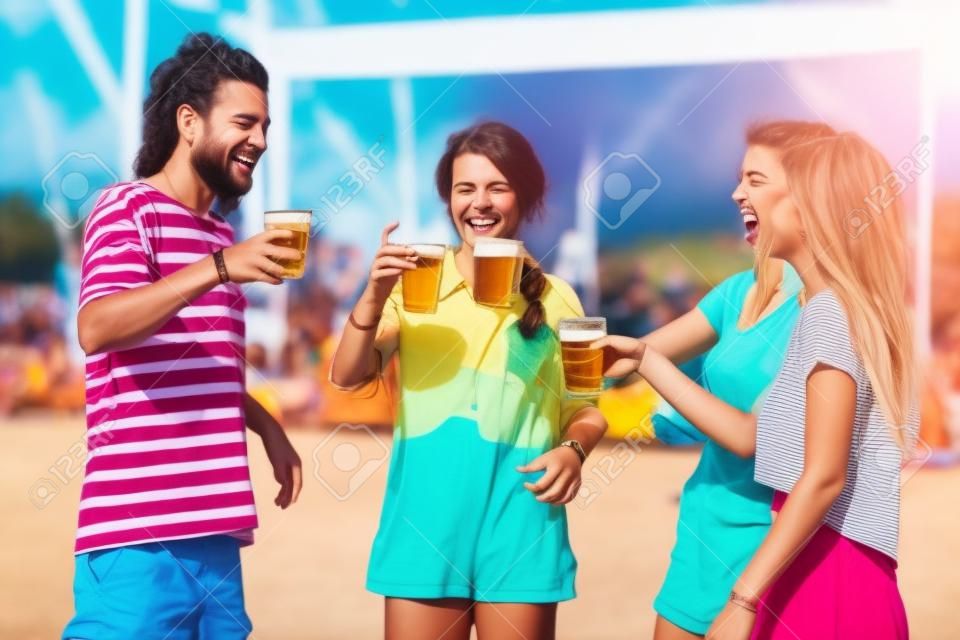 Des amis heureux rient et s'amusent à l'extérieur lors d'un festival de musique. jeunes amis heureux buvant de la bière et s'amusant ensemble au festival de musique. notion de vacances.
