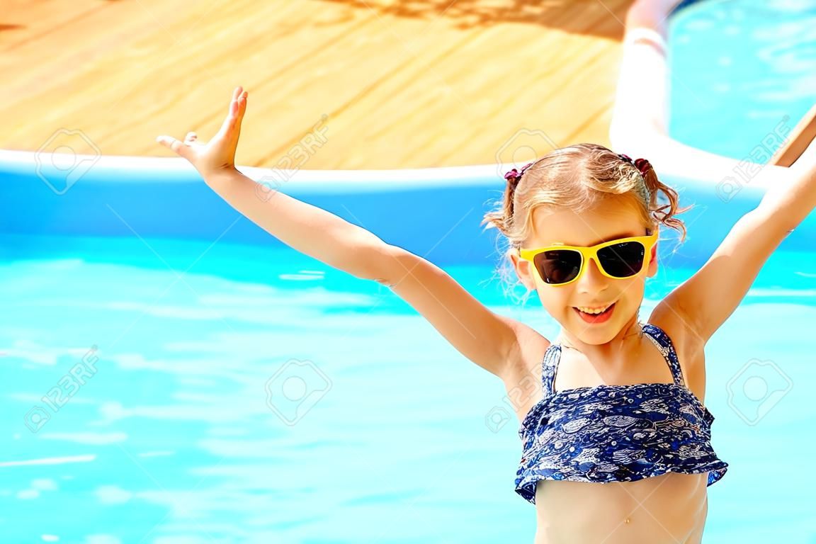 Концепция летних каникул. Маленькая милая девушка в солнцезащитные очки, держась за руки рядом с бассейном.