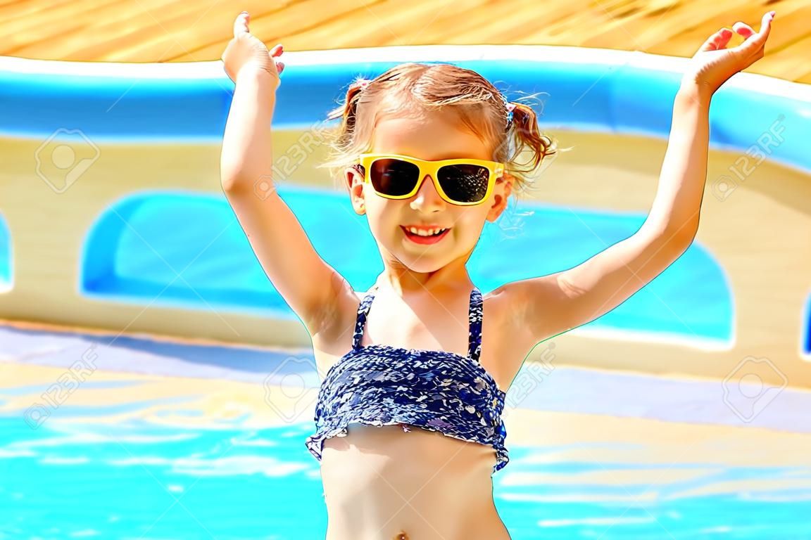 Концепция летних каникул. Маленькая милая девушка в солнцезащитные очки, держась за руки рядом с бассейном.