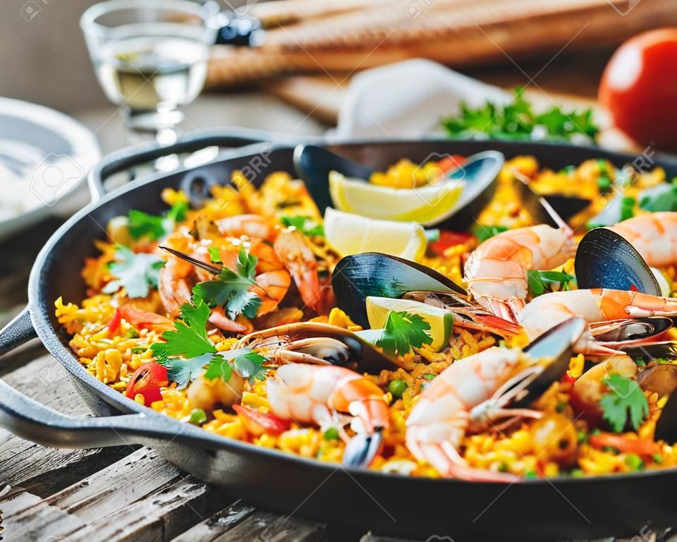 Seafood paella in a frying pan on a wooden background