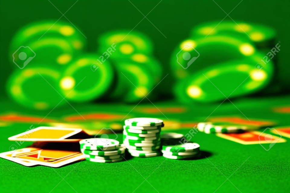 Karten und Chips auf grünem Filz-Casino-Tisch. Abstrakter Hintergrund mit Kopienraum. Thema Glücksspiel, Poker, Casino und Kartenspiele. Casino-Elemente auf Grün. Selektiver Fokus