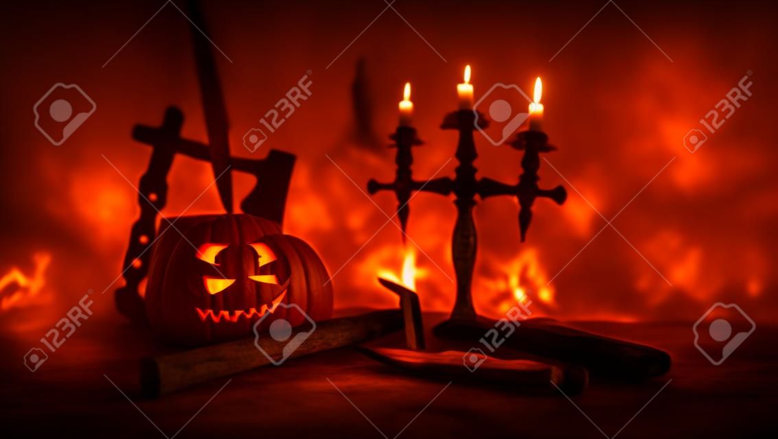 Koncepcja horroru. straszna dynia halloweenowa z rzeźbionymi oczami i uśmiechem z płonącymi świecami i toporem na ciemnym stonowanym tle. Pusta przestrzeń. selektywne skupienie