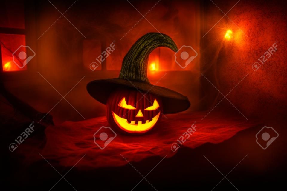 Scary Halloween pumpkin in the mystical house window at night or halloween pumpkin in night on abandoned room with window. selective focus
