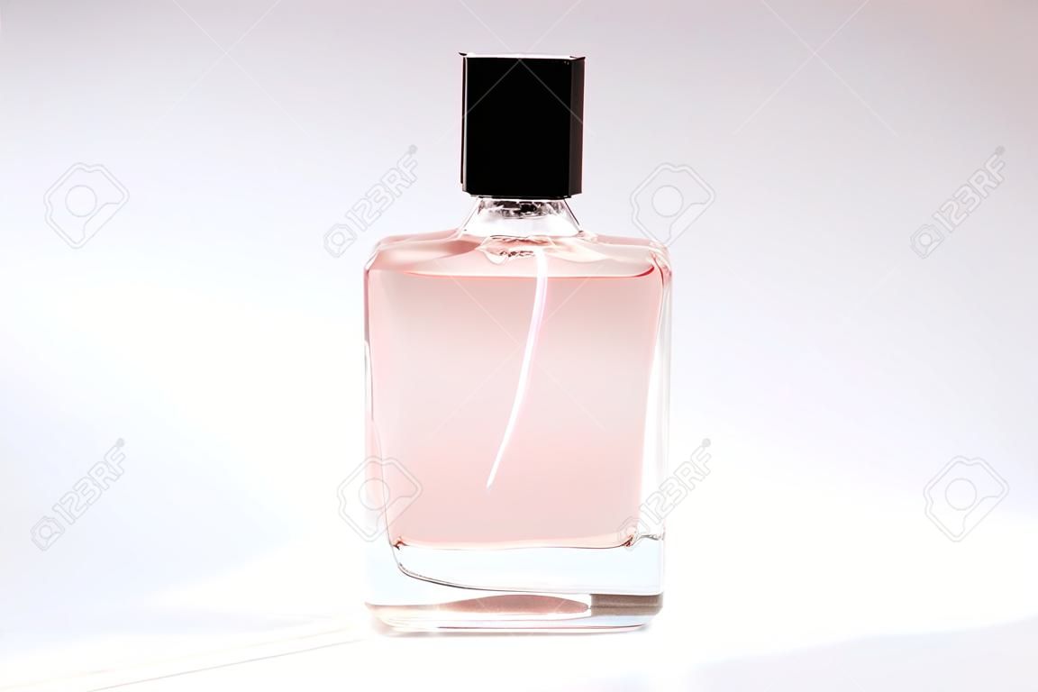 A bottle of spirits of pink color on a white background. Transparent bottle of perfume. Perfume on white.