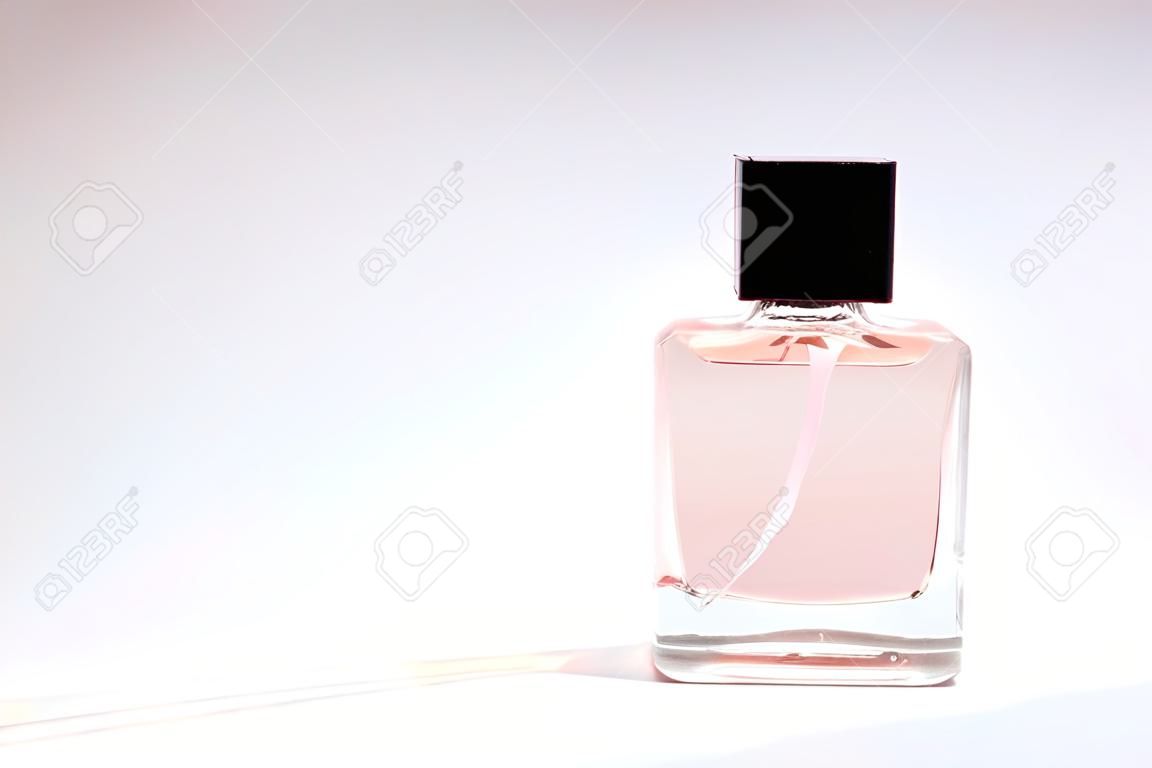 A bottle of spirits of pink color on a white background. Transparent bottle of perfume. Perfume on white.