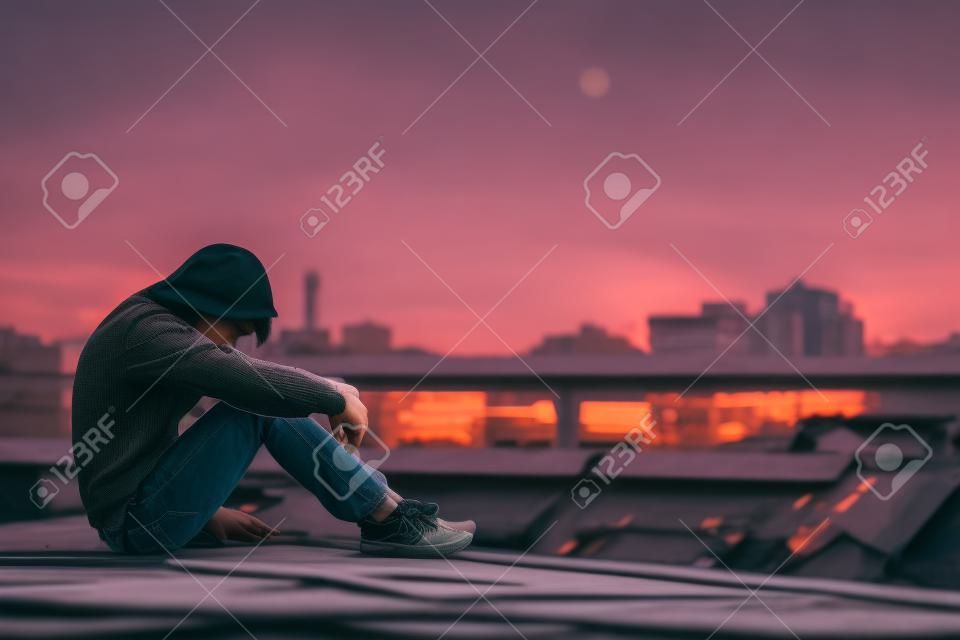 jeune homme asiatique assis sur le toit du bâtiment sale avec le stress de la maladie pendant le temps de soleil dans le concept de la journée du stress . trouble du soleil