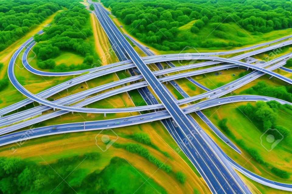 Vista aerea dello svincolo stradale o dell'intersezione autostradale con traffico urbano intenso che accelera sulla strada. Rete di giunzione di trasporto presa da drone.