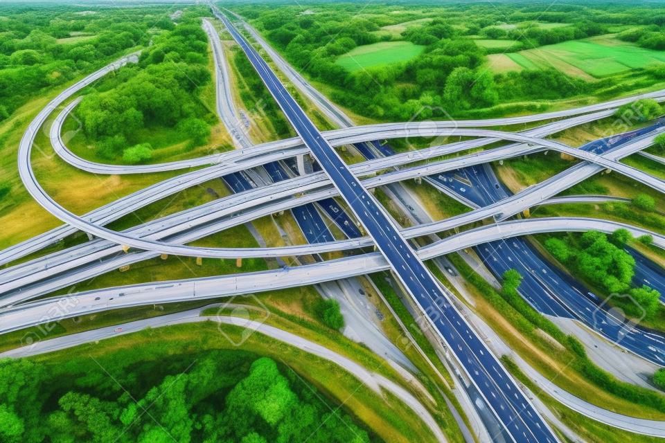 Vista aérea do intercâmbio rodoviário ou cruzamento de rodovias com tráfego urbano movimentado acelerando na estrada. Rede de junção de transporte tomada por drone.